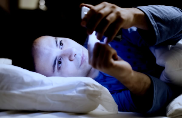 homem com celular na cama